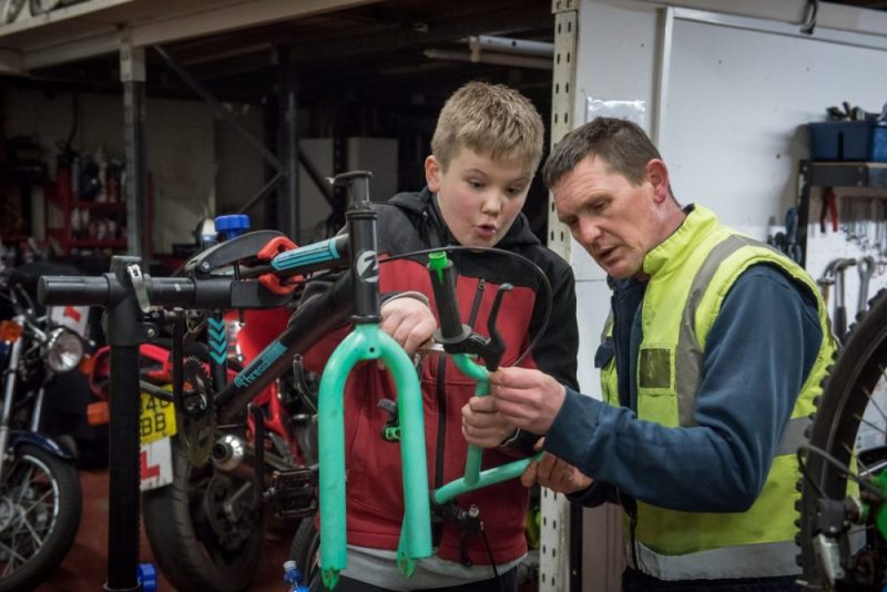 An image from the wheels project in South Tyneside showing a young boy being shown how to fix a bike